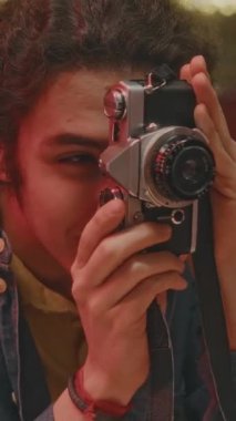 Kot ceketli neşeli beyaz adamın randevu sırasında film kamerasında hatıra fotoğrafı çekerken ya da geceleri neon ışıklı otantik retro tarzı restoranda arkadaşlarıyla buluşurken göğsünü dik tut.