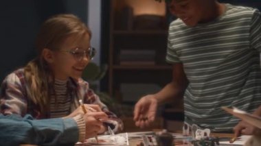 Masa başı oyunu oynayan, zar atan ve akşamları evde tanınmayan oyun ustalarının bahşişlerini dinleyen neşeli çocukların orta boy görüntüsü.