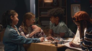 Akşamları evde masa başı oyunu oynayan ve eğlenen bir grup çocuğun yan görüntüsü.