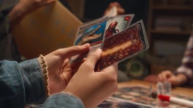 Akşamları evde arkadaşlarıyla oynarken elinde çeşitli karakteristik özellikleri olan üç kart tutan tanınmayan çocuğun yakın çekimi.