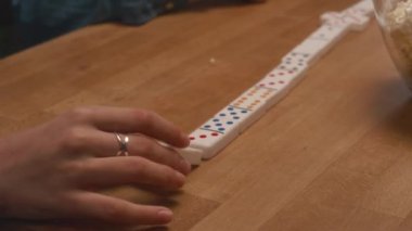 Kimliği belirsiz çocuğun elleri kapalı bir masada oynarken domino taşlarını diziye yerleştiriyor.