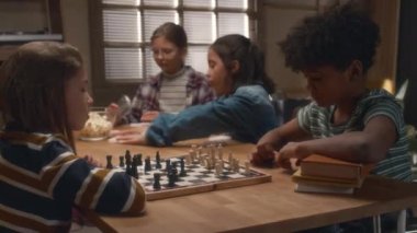 Masa oyunları kulübünde satranç oynayan farklı genç rakiplerin yan görüntüsü. Bir sonraki hamlesini düşünüyor.