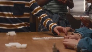 İçeride domino oynayan bir grup çocuğun yan yatmış çekimi, kız oyunun kurallarını anlatıyor.