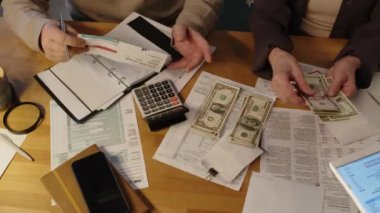 Amerikan dolarlarını sayıp masaya üç deste para koyan tanınmamış yaşlı kadın emeklilerin en iyi çekimleri. Bu arada koca günlük gazetesine kamu hizmetleri suçlamaları yazıyor.