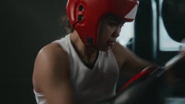 Mavi ve kırmızı yastıklı iki genç bayan boksörün spor salonunda güçlü idman yaparken, rakiplerine güçlü yumruklar atarken ve darbelerden korurken orta boy el pozu.