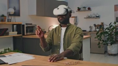 Orta ölçekli Afrikalı Amerikalı iş adamının yüksek teknoloji video ekipmanlarıyla evden internet üzerinden çalışmasını, dokunmatik hareketler yapmasını ve