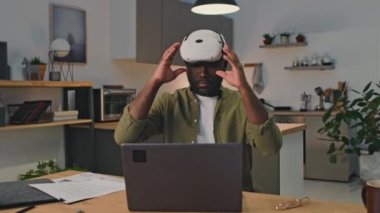 Siyah girişimcinin bilgisayara bağlanıp evdeki artırılmış gerçeklikte çalışırken orta boy görüntüsü.