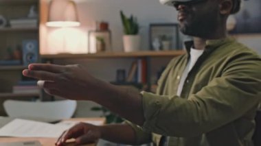 Afro-Amerikalı iş adamının evde çalışırken aktif pencereleri silerken ar gözlükleri kullanırken çekilmiş yan görüntüsü.