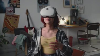 Kızıl saçlı bir kızın evde video gözlüklü okul projesi yaparken orta boy fotoğrafı. Hareketleri kaydırmak, etkin pencereleri genişletmek, artırılmış gerçeklik olasılıklarını deneyimlemek