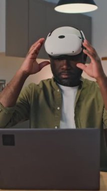 Siyah girişimcinin bilgisayara bağlandığı ve evdeki artırılmış gerçeklikte çalıştığı dikey video görüntüsü.