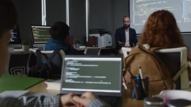 Ortadoğu erkek öğretmeninin projektör ekranının yanındaki yeni konuyu açıklarken orta büyüklükte dizüstü bilgisayarlı bir grup öğrencinin orta boy arka planı.