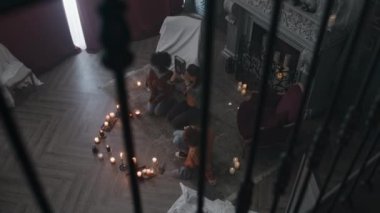 Üç farklı gencin, mumların arasında oturmuş okült kitapla seremoni yaparken, dualar ederken ve terk edilmiş evdeki kötü ruhları uyandırırken en iyi görüntüsü.