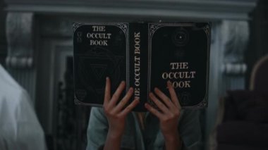 Soluk benizli genç kızın göğüs portresi eski okült kitap indirdi, şeytan tarafından ele geçirildi ve eski boş malikanede kameraya baktı