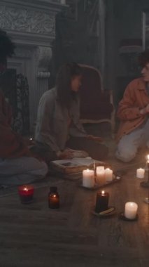 Smokey Dark House 'daki dua ayini sırasında kızın şeytanlaştırılmasının ve çeşitli korkmuş arkadaşlarının yardım etmeye çalışmasının dikey yan görüntüsü.