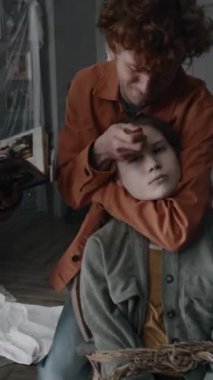 Şeytan ruhlu bir kızın alnına yanan palo santo çubuğuyla haç çizen genç adamın dikey görüntüsü terk edilmiş malikanede şeytan çıkarma ayinleri sırasında sandalyeye iple bağlanmış bir kız.