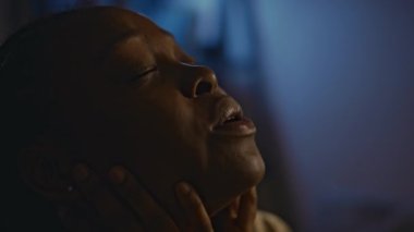 Gece travmatik geri dönüşler ve travma sonrası stres bozukluğundan dolayı derin nefes almaya çalışan Afrikalı Amerikalı genç bir kadının yan görüntüsü.