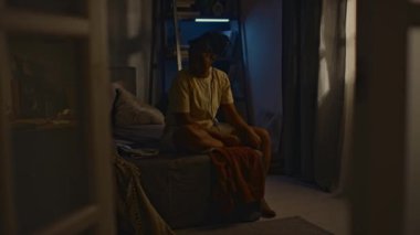 Genç siyahi bir kadının gece yatakta fotoğraflara baktığı, dizlerine sarıldığı, uyanık kaldığı, mutsuz ve yalnız hissettiği, uykusuzluk çektiği bir fotoğraf.