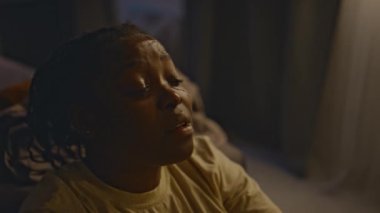 Afrika kökenli Amerikalı bir kadının gece yatağında oturup ağlarken, çocuğunu kaybettiği için istifa edemezken, travmatik anılar yaşarken.