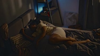 Travma sonrası stres bozukluğu olan, korkunç kabuslardan uyanan ve geceleri travmatik anılarla yaşayan genç siyahi bir kadının yüksek açılı çekimleri.