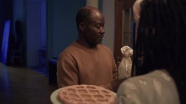 Yetişkin siyah büyükbabanın koridorda durup, oğluyla ailesini selamlarken, şarap şişesine bakarken, torununa sarılırken, akşam yemeğine oturmadan önce, geliniyle sohbet ederken orta derece yavaş bir pozu.