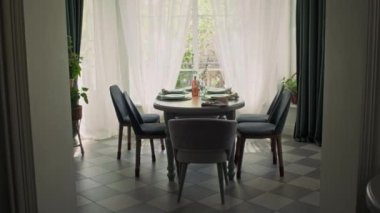 Evde, geniş Fransız penceresinin önünde beş sandalye, tabak, çatal bıçak seti, tatilde ya da hafta sonu aile yemeği için hazırlanmış masalardan çekilen kimse yok.