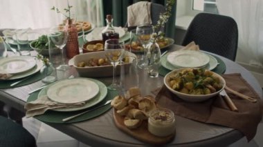 Orta boy hiç kimse yemek odasında öğle yemeği için hazır yemek, fırında patates, kızarmış tavuk, dilimlenmiş ekmek, humus, içecekler, tabaklar, şarap bardakları, çatal bıçaklar, gündüz vakti
