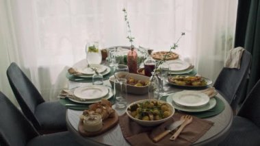 Yemek odasında aile şenliği için hazırlanmış hiç kimse yok. Fırında patates, kızarmış et, ekmek, humus, turta, içecekler, tabaklar, şarap bardakları, çatal bıçaklar.