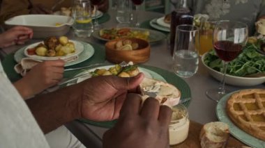 Ailesiyle ya da arkadaşlarıyla akşam yemeğinde, kızarmış ekmeğe tereyağı ya da ezme süren, kızarmış tavuk ve sebzeyle kaplanmış, tanınmayan genç Afrikalı Amerikalı kadının elleri.