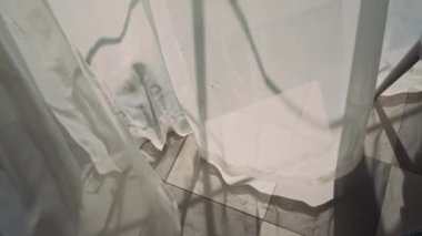 Yakın planda beyaz pencere perdelerinden çekilen kimse yok. Güneşli bir yaz gününde aile evinde hafif bir esinti ve yerde hareket eden gölgeler yok.