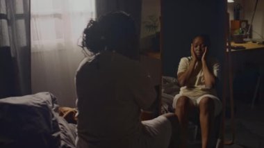 Genç Afrikalı Amerikalı bir kadının yatakta aynanın önünde otururken, fiziksel bedeninden koptuğunu, yüzlerine ve aynalarına dokunduğunu, gerçeği fark etmediğini gösteren bir sahne.