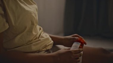 İç çamaşırlı, koyu tenli, isimsiz bir kadının avucunun içine bir avuç dolusu sakinleştirici dökerek, ilaç alıp almama konusunda bir ikilemde kalmasının yan görüntüsü.