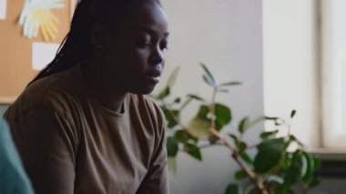 Genç Afrikalı Amerikalı kadının travmatik geçmişteki olaylardan bahsederken ve modern psikoloji merkezindeki travma sonrası terapi seansında duygularını açıklamakta zorlanırken.