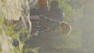 Beyaz kadın turistin sırt çantasıyla nehre inerken ve yazın doğa yürüyüşü yaparken çekilen dikey görüntüsü.