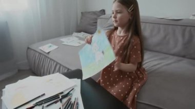 Kafkasyalı anaokulu kızının Afrika kökenli Amerikalı genç dadıya çizimlerini gösterirken evde birlikte vakit geçirirken orta boy bir fotoğrafı.