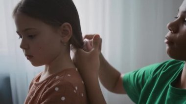 Kafkas 'lı küçük bir kızın saçını tarayıp, ördüğü göğüs röntgeni. Afrikalı Amerikalı genç bebek bakıcısı.