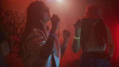 Kırmızı neon ışıklı gece kulübündeki yılbaşı partisinde elektronik dans müziğine giden ve çılgın partilere katılan çeşitli eski moda kıyafetleri içinde el kamerasıyla çekilen çeşitli kadın arkadaşlar.