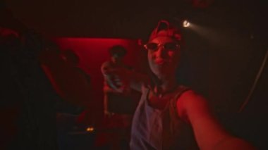 Gece kulübünde kırmızı neon ışıklı ve yanıp sönen bir gece kulübünde havalı bir adamla dans ederken genç ve havalı bir bayanın el kamerasıyla kendini ön kameraya kaydettiği görüntüler.