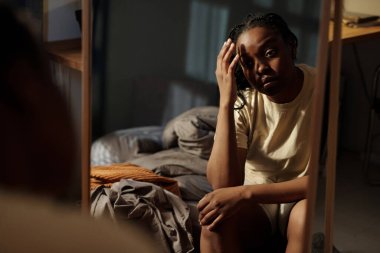 Genç kırık kalpli ve yalnız bir kadın uykusuzluk sırasında gece yarısı yatakta otururken kafasına dokunup aynaya bakıyor.