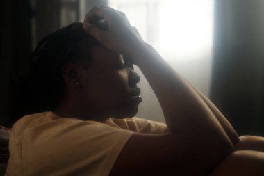 Travma sonrası stres bozukluğundan acı çekerken ellerini ve gözlerini kapalı tutan çaresiz genç bir kadın.