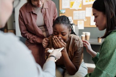 Kadın psikoloğun önünde oturup gözyaşlarını silmek için mendilini uzatırken acı çeken ağlayan Afrikalı Amerikalı kadın.