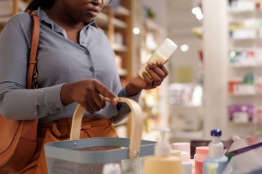 Genç bayan alıcının kozmetik süpermarkette yeni bir güzellik ürününü seçerken kendini sevdiren ürünlerle birlikte görüntüde durduğu görüntüler.