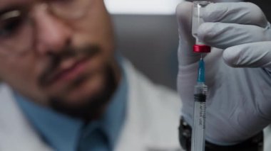 Bulanık bağışıklık bilimcilerin kapatılması klinikte aşı yapmadan önce ilaç şişesinden çekilen koruyucu eldivenler ve şırınga ile havanın alınması