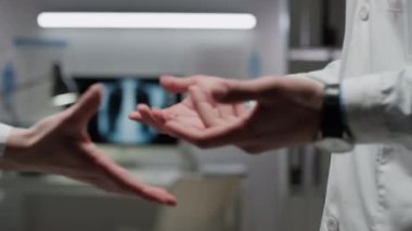 Önlüklü, iş konularını tartışan ve modern hastanede el sıkışan tanınmayan tıp çalışanlarının orta bölüm fotoğrafları.