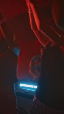 Retro y2k kıyafetleriyle dans eden, elektronik müzik eşliğinde el sallayan, kulüpte kırmızı neon ışıkla takılan ve geceleri yanıp sönen bir grup enerjik çılgın genç.