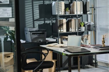 Avukatlık bürosunun, dizüstü bilgisayarlı koltuk ve masadan oluşan bir kısmı, kağıt belgeli siyah klasör ve açık defterden oluşan bir kısmı.