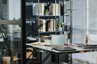 Etrafı kalem ve mali evraklarla dolu açık bir defterle çevrili dizüstü bilgisayar avukatın iş yerinin tam ortasında duruyor.