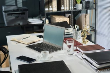 Avukat dizüstü bilgisayarlı masa, çalışma notlarıyla birlikte açık not defteri, bir bardak su, kahve veya çay, cep telefonu ve diğer malzemeler.