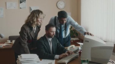 Resmi kıyafetli çeşitli meslektaşların orta boy toplu portresi, eski bilgisayar üzerinde çalışan ve 90 'larda retro ofis olan kameraya bakan ofis çalışanlarının etrafında toplandı.