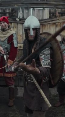 Kafkaslı, zırhlı, mızraklı, kalenin kapısında asker birliğiyle dikey duran cesur beyaz erkek savaşçının orta boy portresi.