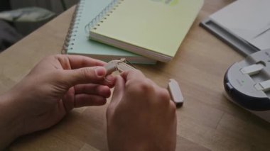 İşitme engelli, koklear implantın parçalarını bakımdan sonra monte eden, şarj aletinden yeni pil çıkaran ve yerleştiren isimsiz bir gencin elleri.